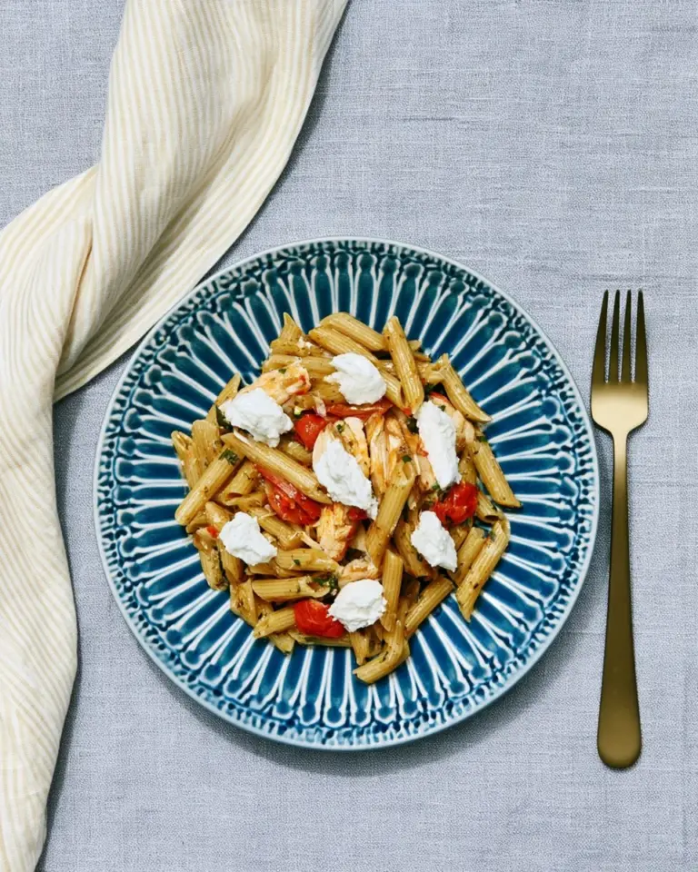 Penne z zielonym pesto, kurczakiem i pomidorkami na talerzu